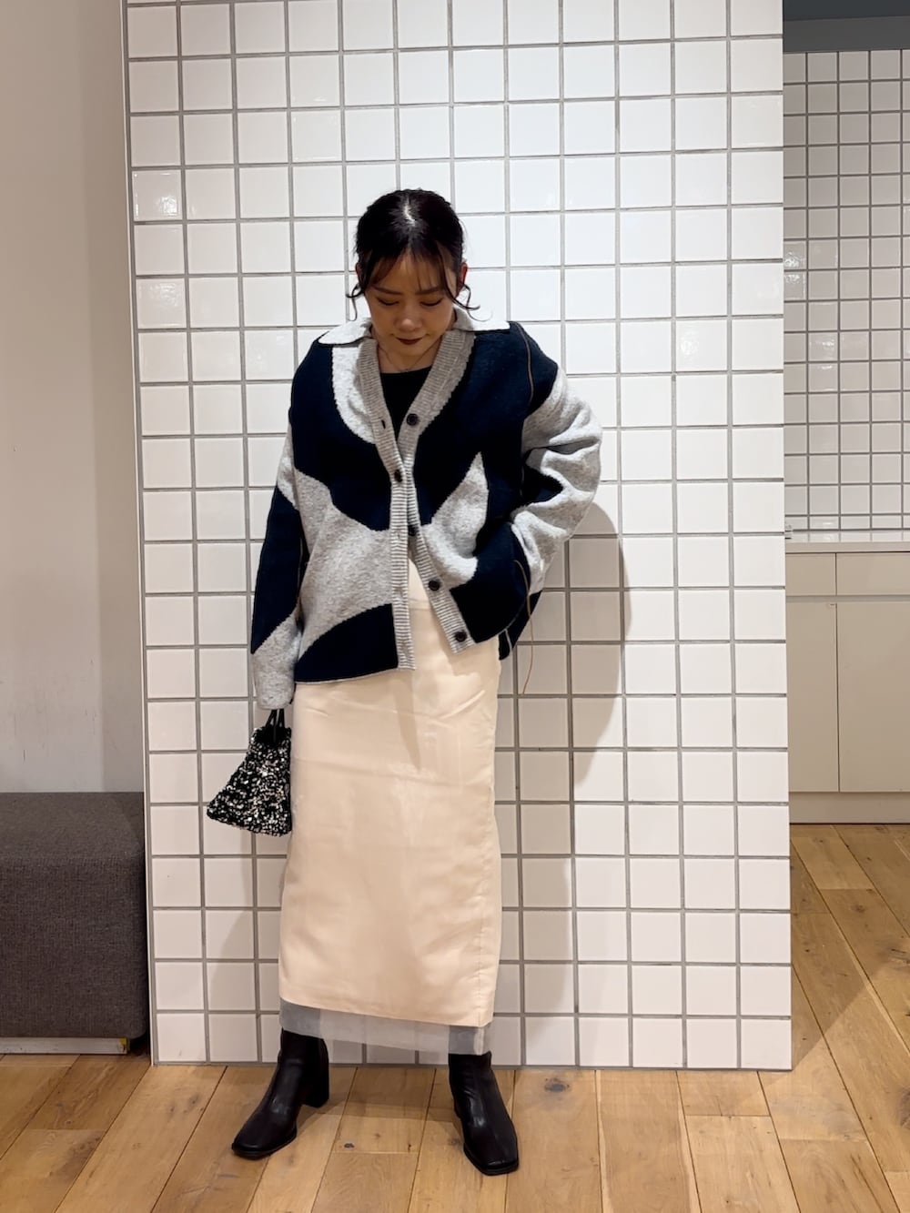 ホワイト系のカーディガン/ボレロ、ブルー系のニット/セーター、シルバー系のショルダーバッグを着用したレディースの冬コーディネートの2枚目の写真