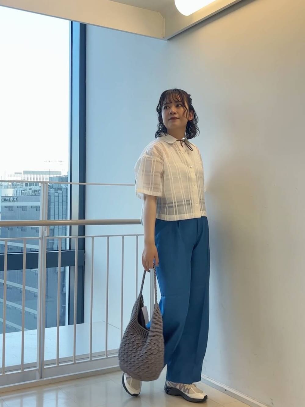 グレー系のハンドバッグ、ホワイト系のスニーカー、ブルー系のその他パンツを着用したレディースの春コーディネートの3枚目の写真