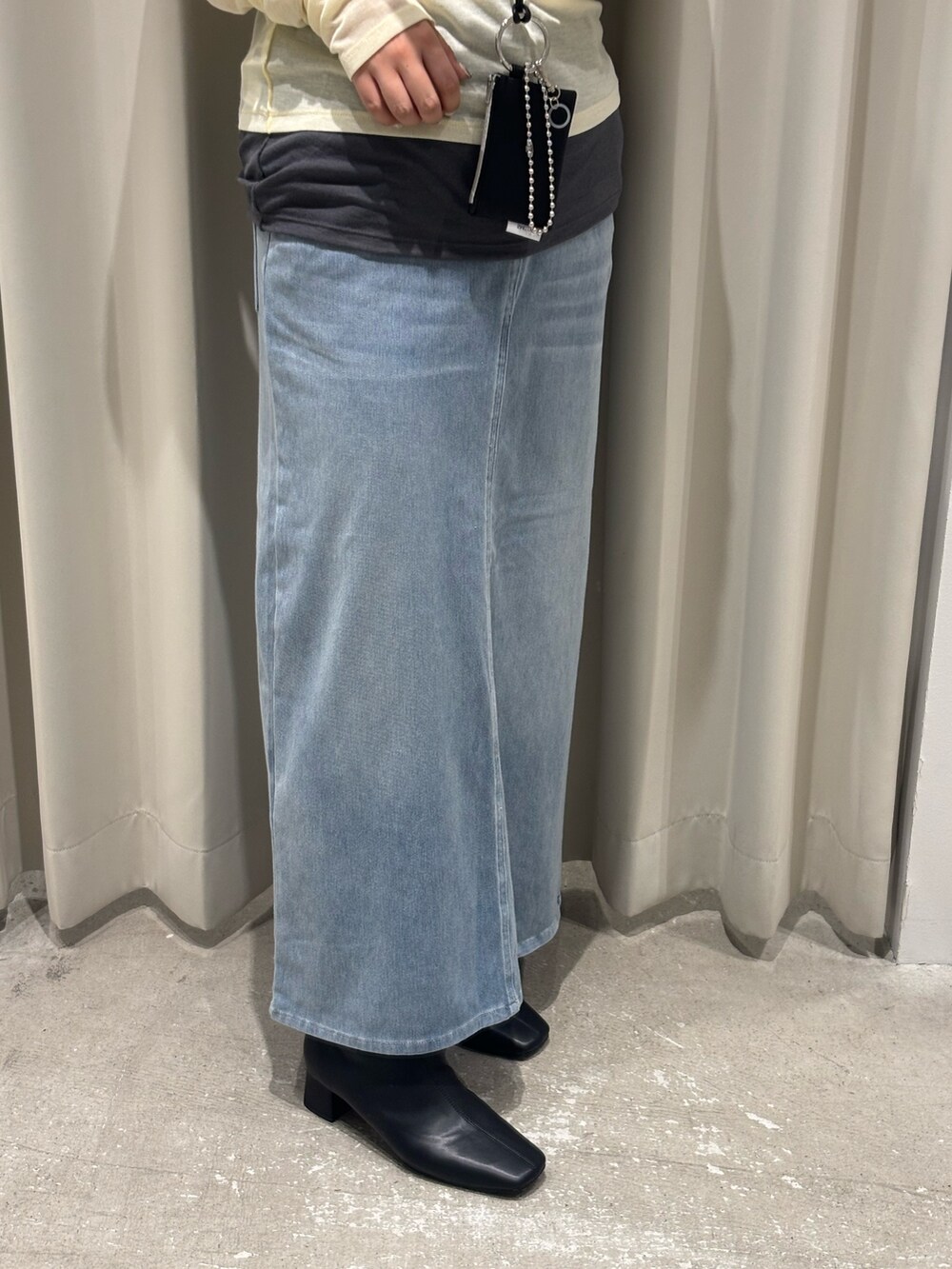 イエロー系のTシャツ/カットソー、ブルー系のスカート、ブラック系のブーツを着用したレディースの秋コーディネートの3枚目の写真