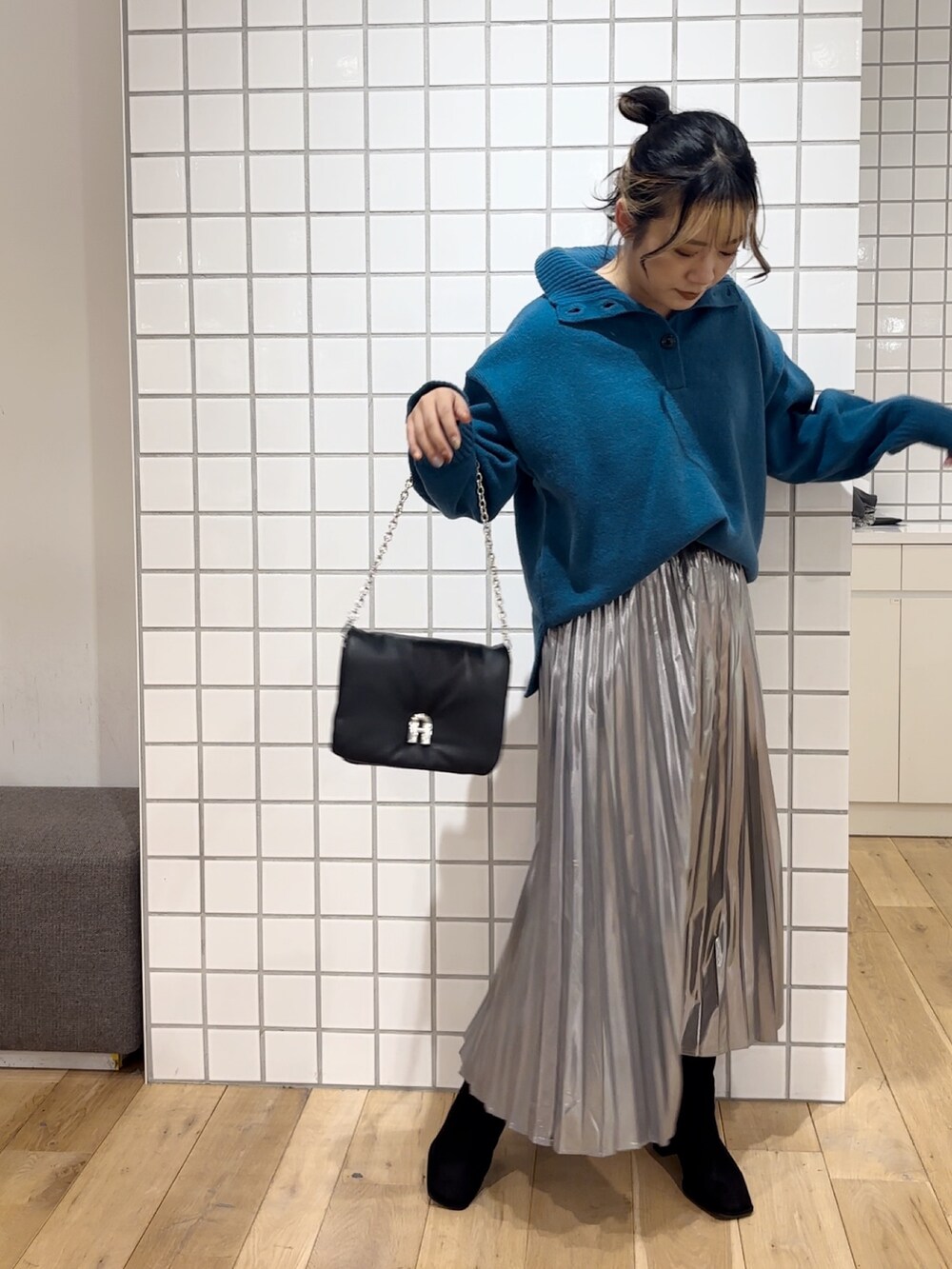 ブルー系のニット/セーター、シルバー系のスカート、ブラック系のショルダーバッグを着用したレディースの秋コーディネートの3枚目の写真