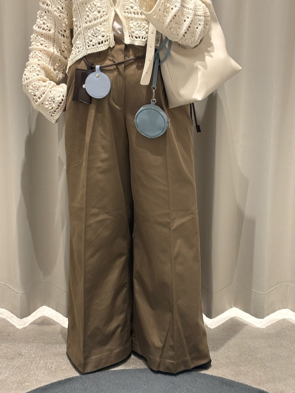 ホワイト系のカーディガン/ボレロ、ホワイト系のキャミソール、ベージュ系のハンドバッグを着用したレディースの春コーディネートの3枚目の写真