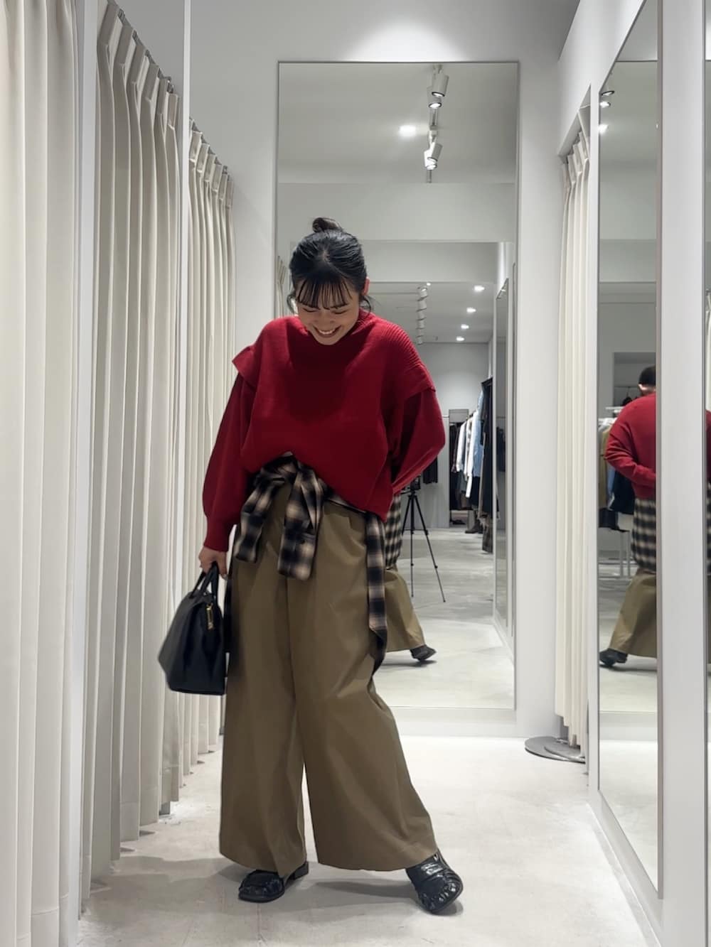 レッド系のニット/セーター、ブラウン系のシャツ/ブラウス、ブラック系のローファーを着用したレディースの秋コーディネートの2枚目の写真