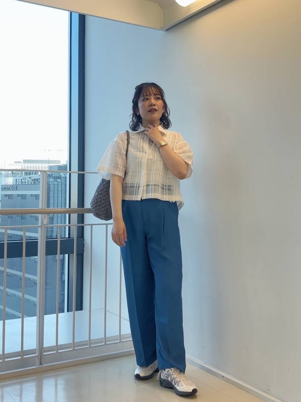 グレー系のハンドバッグ、ホワイト系のスニーカー、ブルー系のその他パンツを着用したレディースの春コーディネートの2枚目の写真