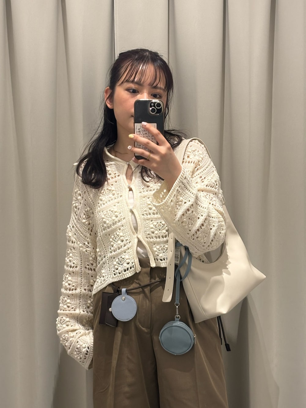 ホワイト系のカーディガン/ボレロ、ホワイト系のキャミソール、ベージュ系のハンドバッグを着用したレディースの春コーディネートの2枚目の写真