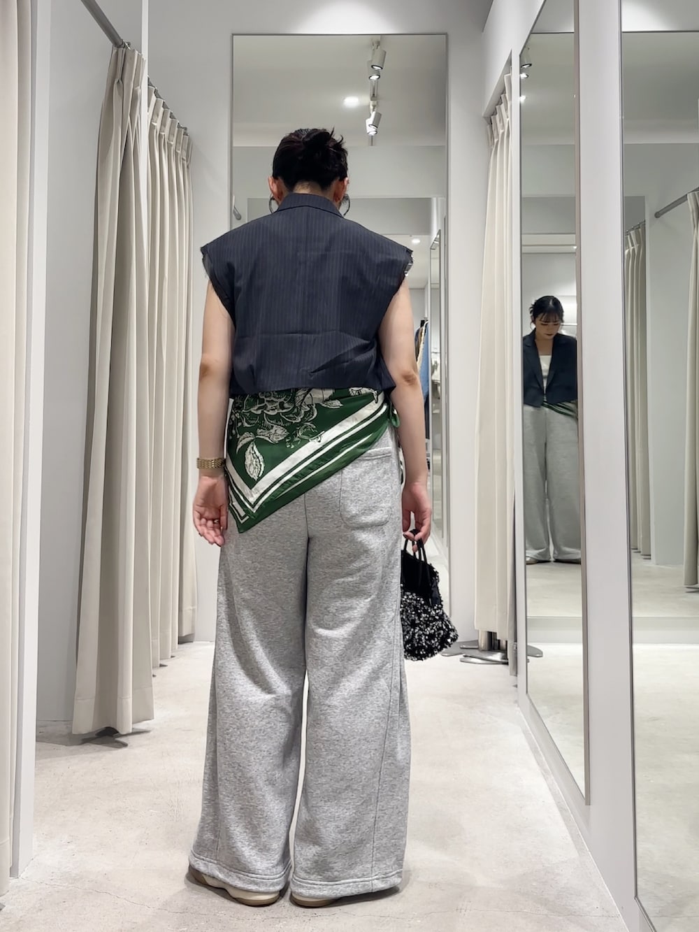 グレー系のベスト、グレー系のその他パンツ、シルバー系のショルダーバッグを着用したレディースの秋コーディネートの3枚目の写真