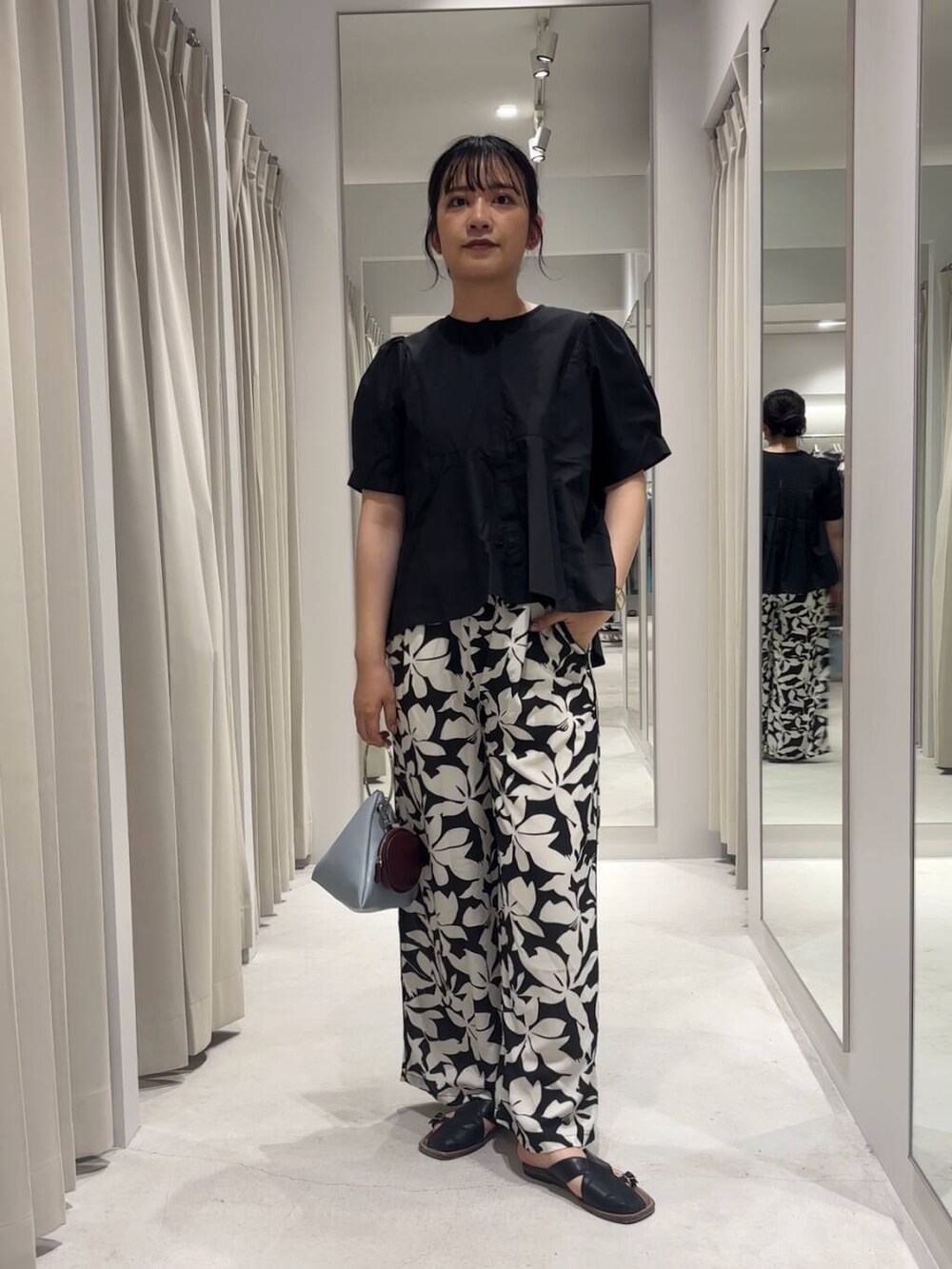 ブルー系のハンドバッグ、ブラック系のその他パンツ、ブラック系のシャツ/ブラウスを着用したレディースの夏コーディネートの5枚目の写真