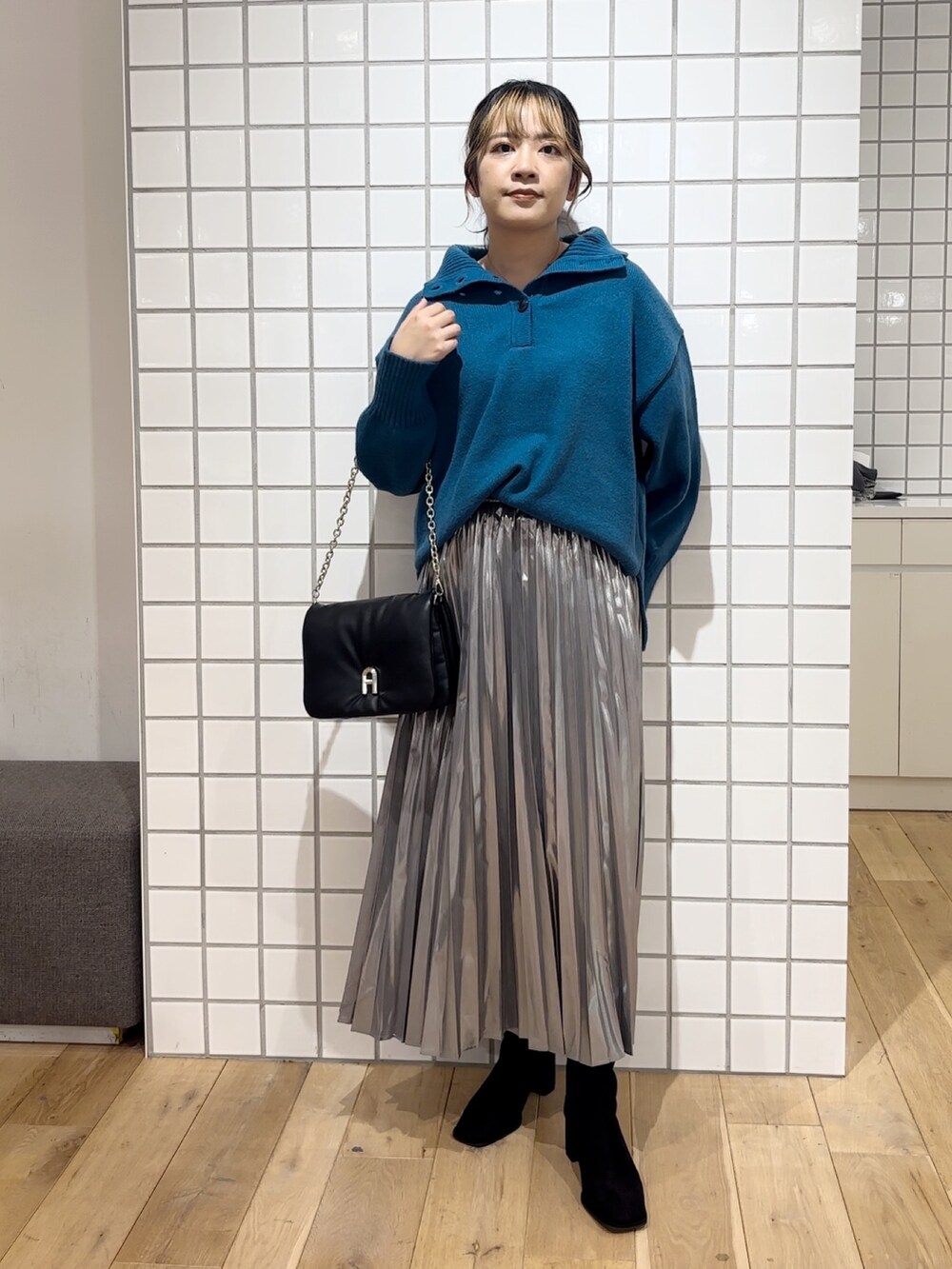 ブルー系のニット/セーター、シルバー系のスカート、ブラック系のショルダーバッグを着用したレディースの秋コーディネートの2枚目の写真