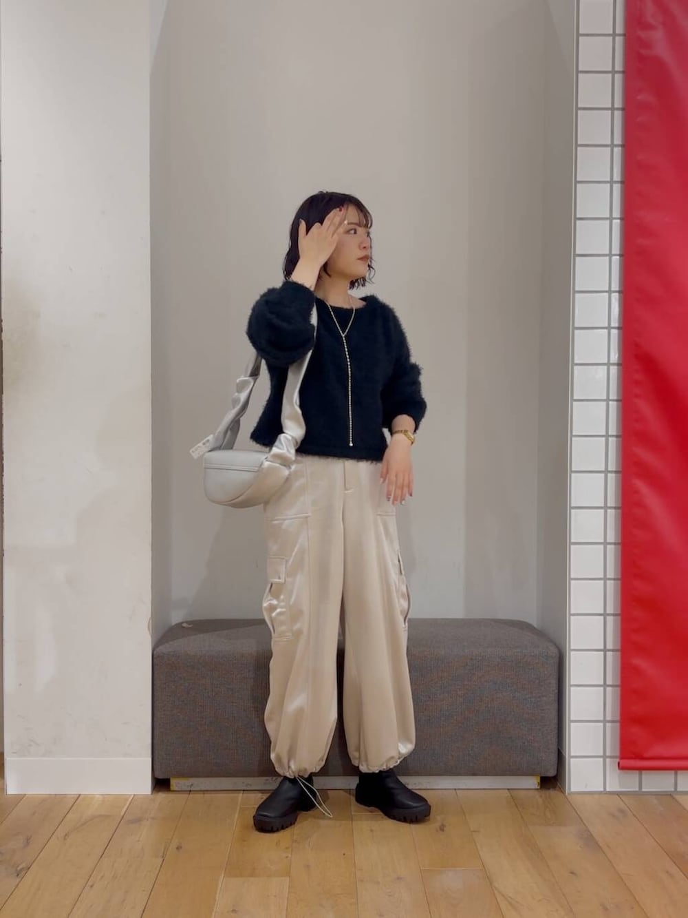 シルバー系のハンドバッグ、ブラック系のブーツ、ブラック系のニット/セーターを着用したレディースの冬コーディネートの2枚目の写真