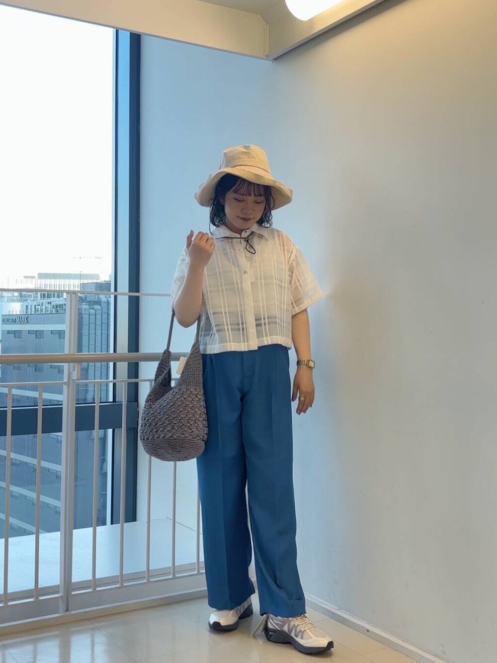 グレー系のハンドバッグ、ホワイト系のスニーカー、ブルー系のその他パンツを着用したレディースの春コーディネートの4枚目の写真