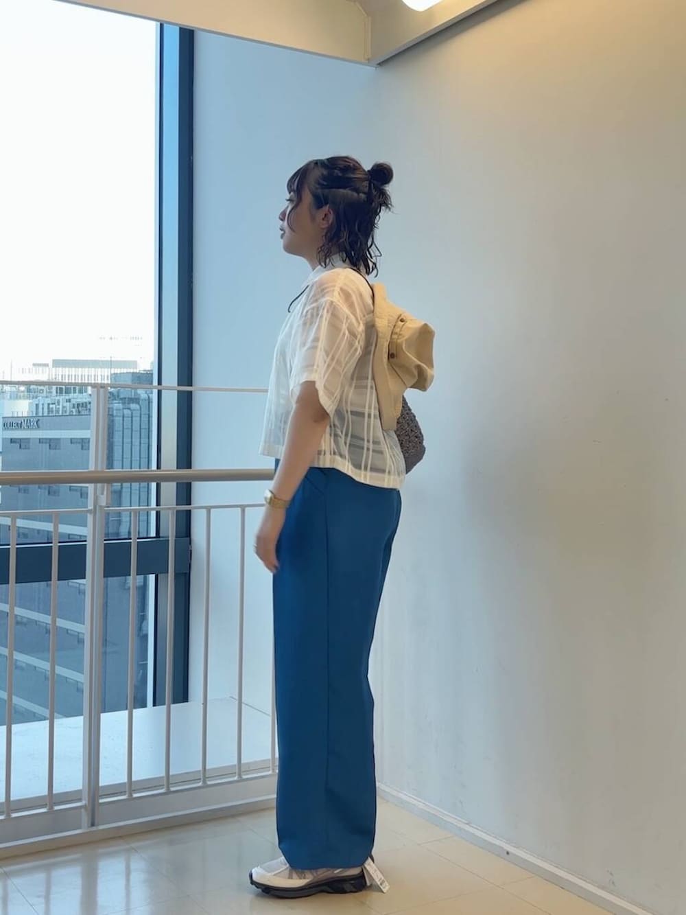 グレー系のハンドバッグ、ホワイト系のスニーカー、ブルー系のその他パンツを着用したレディースの春コーディネートの6枚目の写真