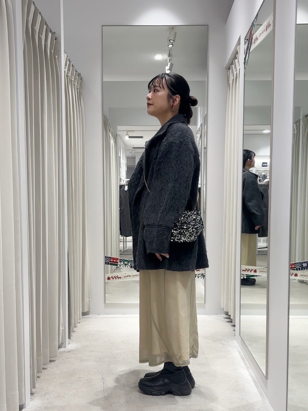 ベージュ系のワンピース、グレー系のその他アウター、シルバー系のショルダーバッグを着用したレディースの冬コーディネートの2枚目の写真