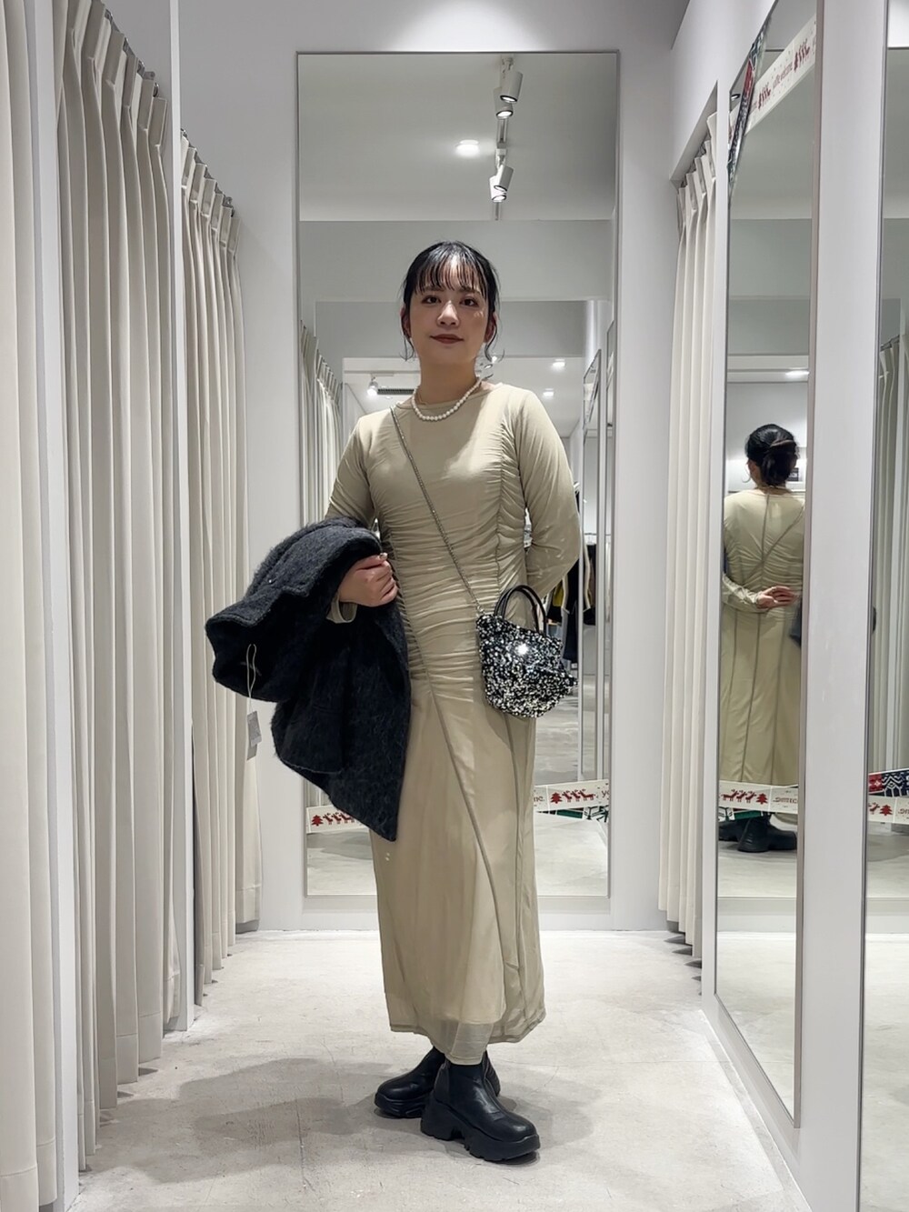 ベージュ系のワンピース、グレー系のその他アウター、シルバー系のショルダーバッグを着用したレディースの冬コーディネートの4枚目の写真