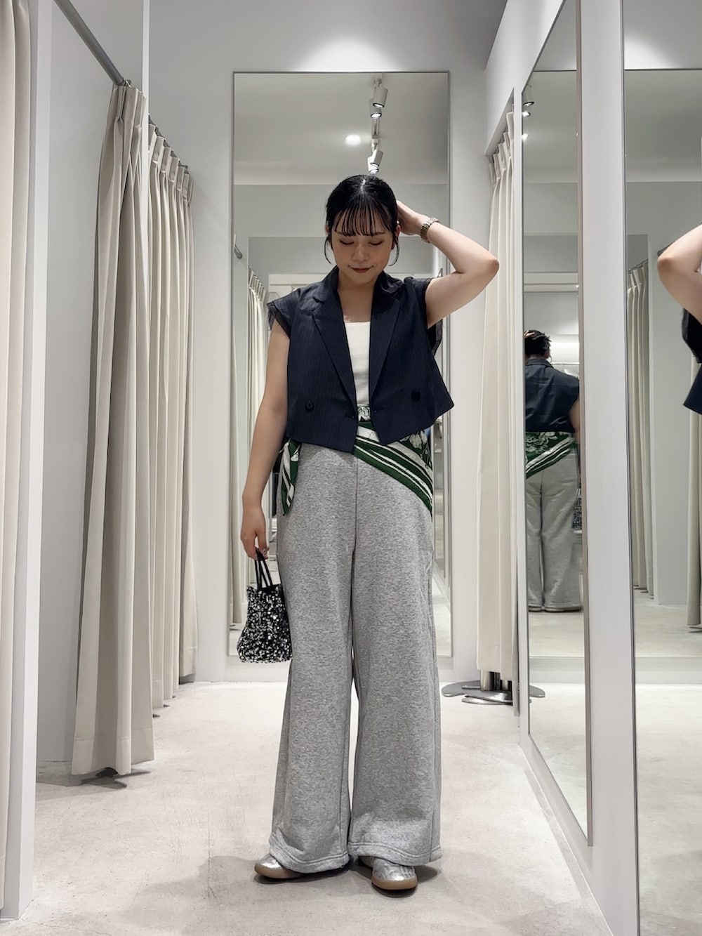 グレー系のベスト、グレー系のその他パンツ、シルバー系のショルダーバッグを着用したレディースの秋コーディネートの2枚目の写真