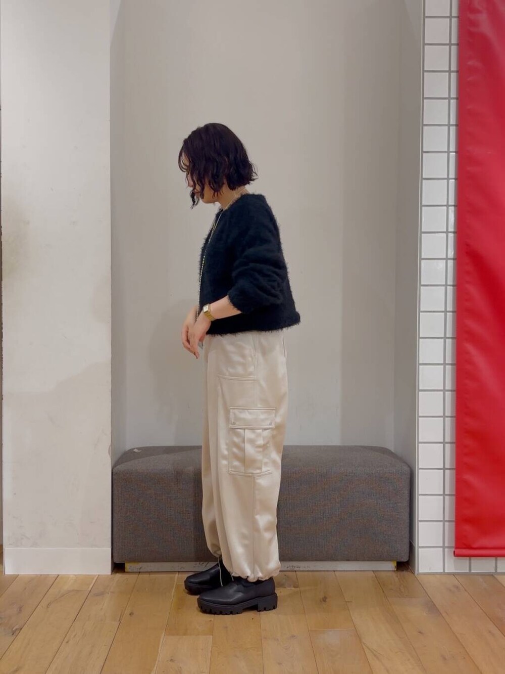 シルバー系のハンドバッグ、ブラック系のブーツ、ブラック系のニット/セーターを着用したレディースの冬コーディネートの4枚目の写真