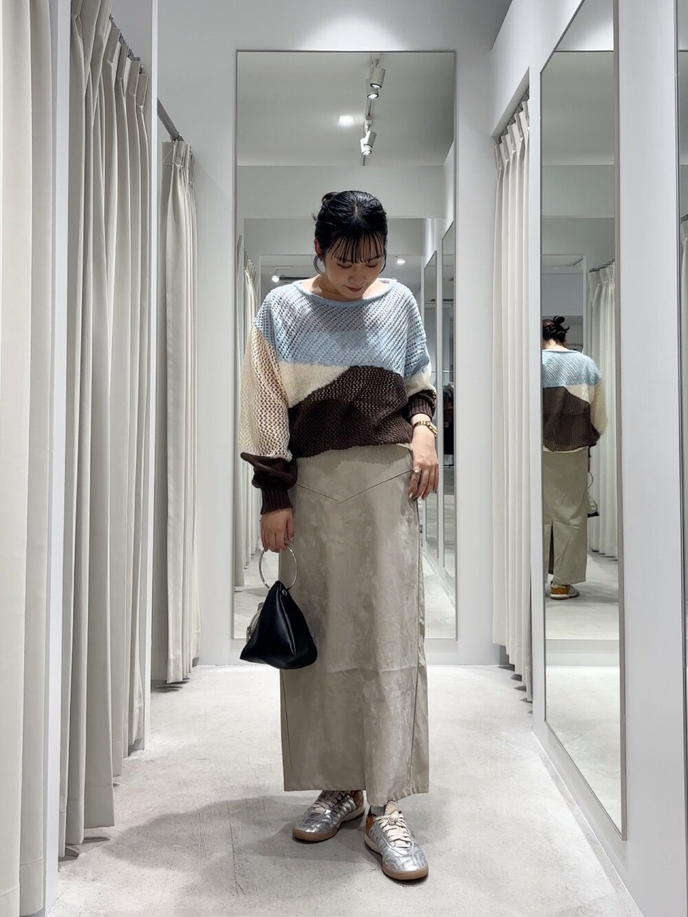 ブルー系のニット/セーター、ベージュ系のスカート、ブラック系のハンドバッグを着用したレディースの秋コーディネートの2枚目の写真
