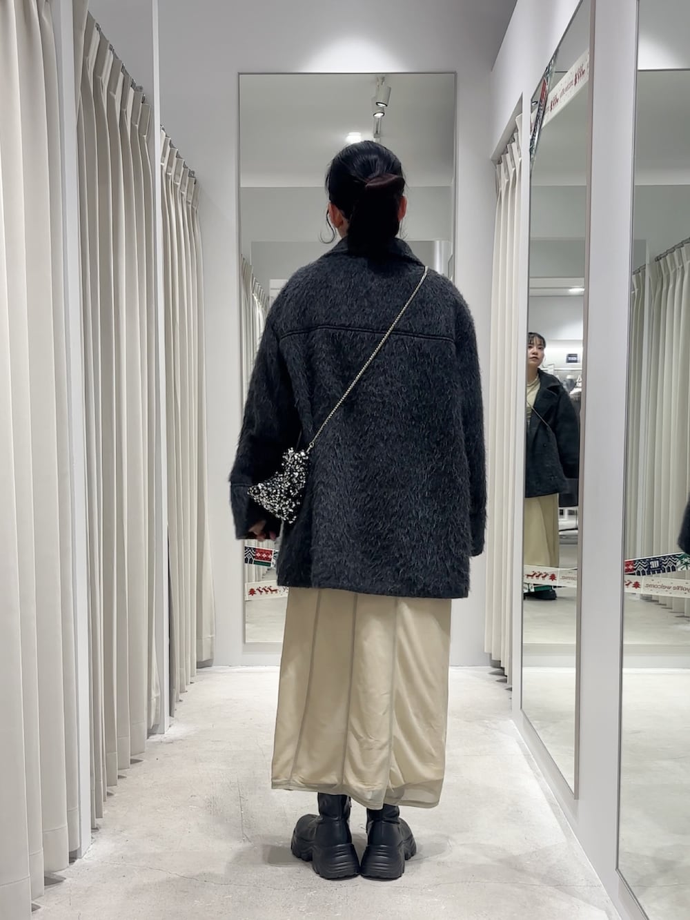 ベージュ系のワンピース、グレー系のその他アウター、シルバー系のショルダーバッグを着用したレディースの冬コーディネートの3枚目の写真