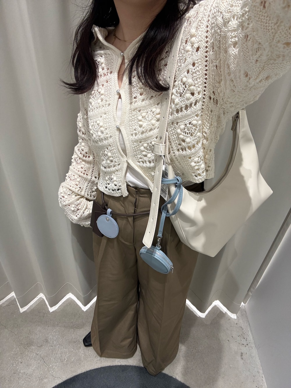 ホワイト系のカーディガン/ボレロ、ホワイト系のキャミソール、ベージュ系のハンドバッグを着用したレディースの春コーディネートの4枚目の写真