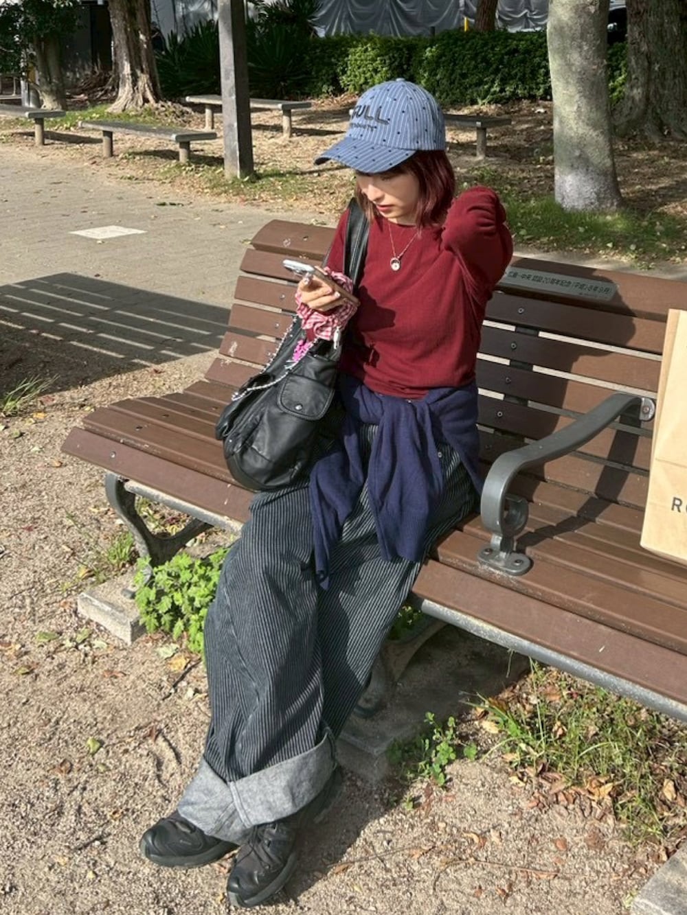 ブラック系のスニーカー、ブラック系のデニムパンツ、ブルー系のニット/セーターを着用したレディースの冬コーディネートの2枚目の写真