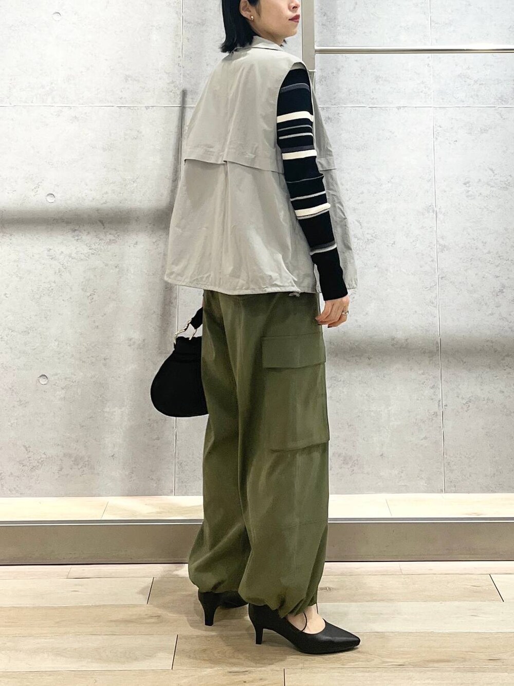 グレー系のベスト、ブラック系のハンドバッグ、グリーン系のカーゴパンツを着用したレディースの冬コーディネートの7枚目の写真