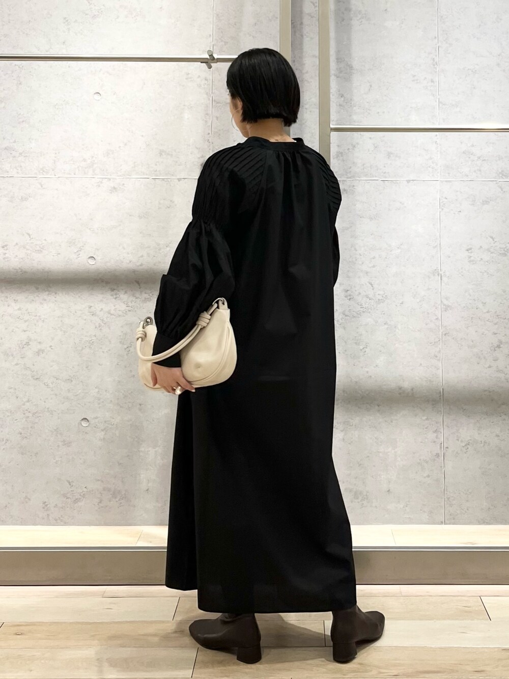 ブラック系のワンピース/ドレス、ブラウン系のブーツ、ホワイト系のショルダーバッグを着用したレディースの秋コーディネートの4枚目の写真