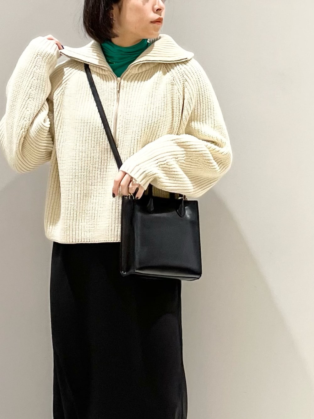 ブラック系のスカート、ブラック系のショルダーバッグ、ブラック系のブーツを着用したレディースの冬コーディネートの2枚目の写真