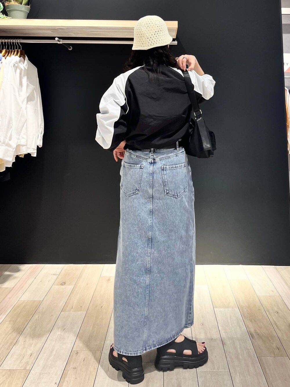 ブルー系のデニムスカート、ブラック系のショルダーバッグ、ブラック系のサンダルを着用したレディースの春コーディネートの3枚目の写真