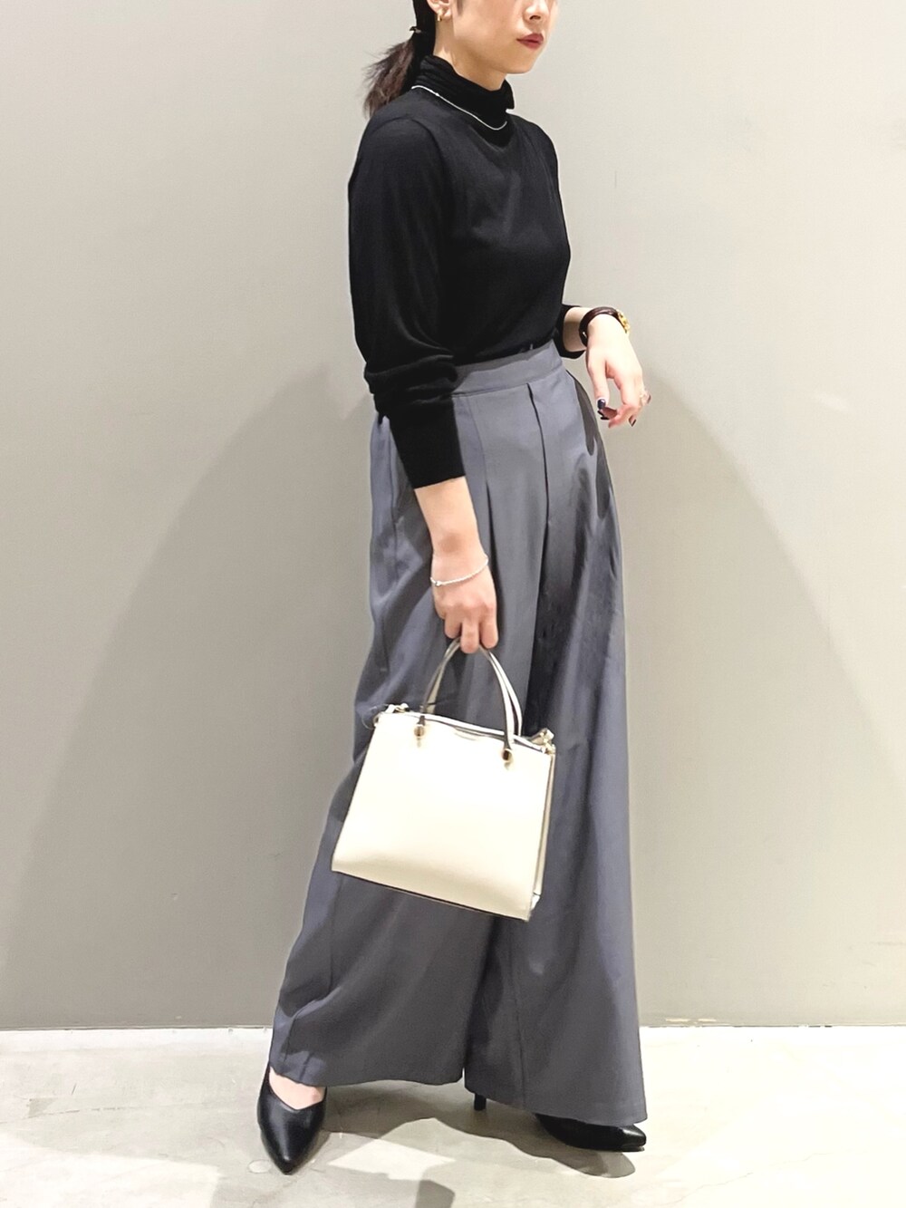 ブラック系のパンプス、ホワイト系のショルダーバッグ、ブラック系のTシャツ/カットソーを着用したレディースの秋コーディネートの3枚目の写真