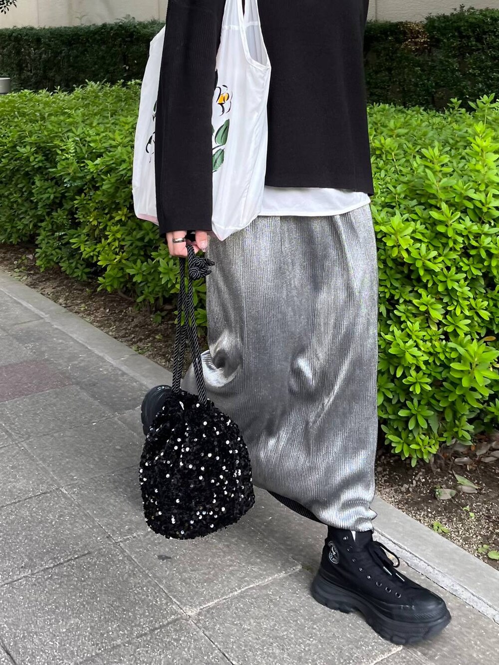 ブラック系のニット/セーター、ホワイト系のTシャツ/カットソー、シルバー系のスカートを着用したレディースの秋コーディネートの3枚目の写真