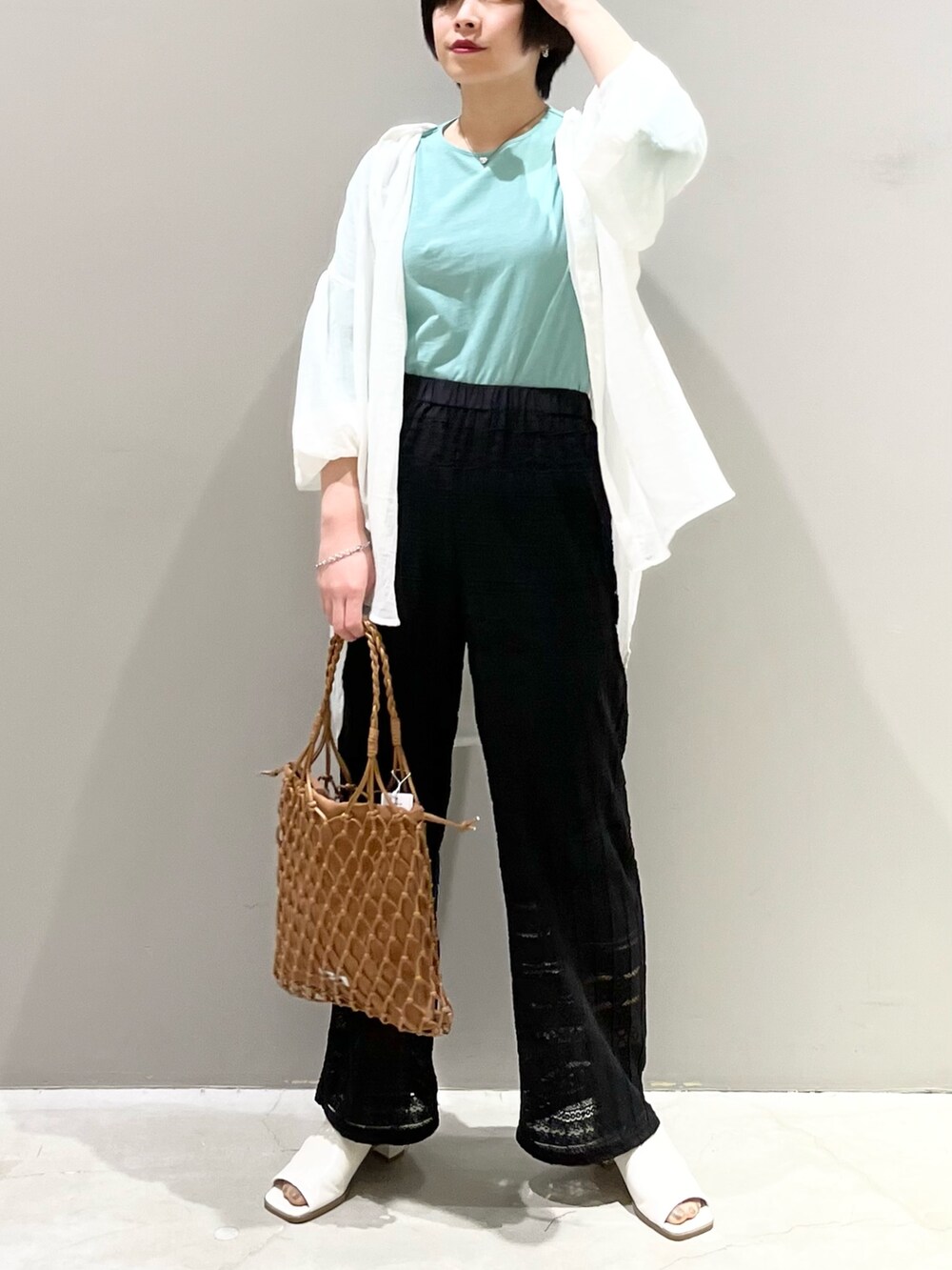 ブラック系のその他パンツ、ホワイト系のサンダル、ベージュ系のバッグを着用したレディースの春コーディネートの4枚目の写真