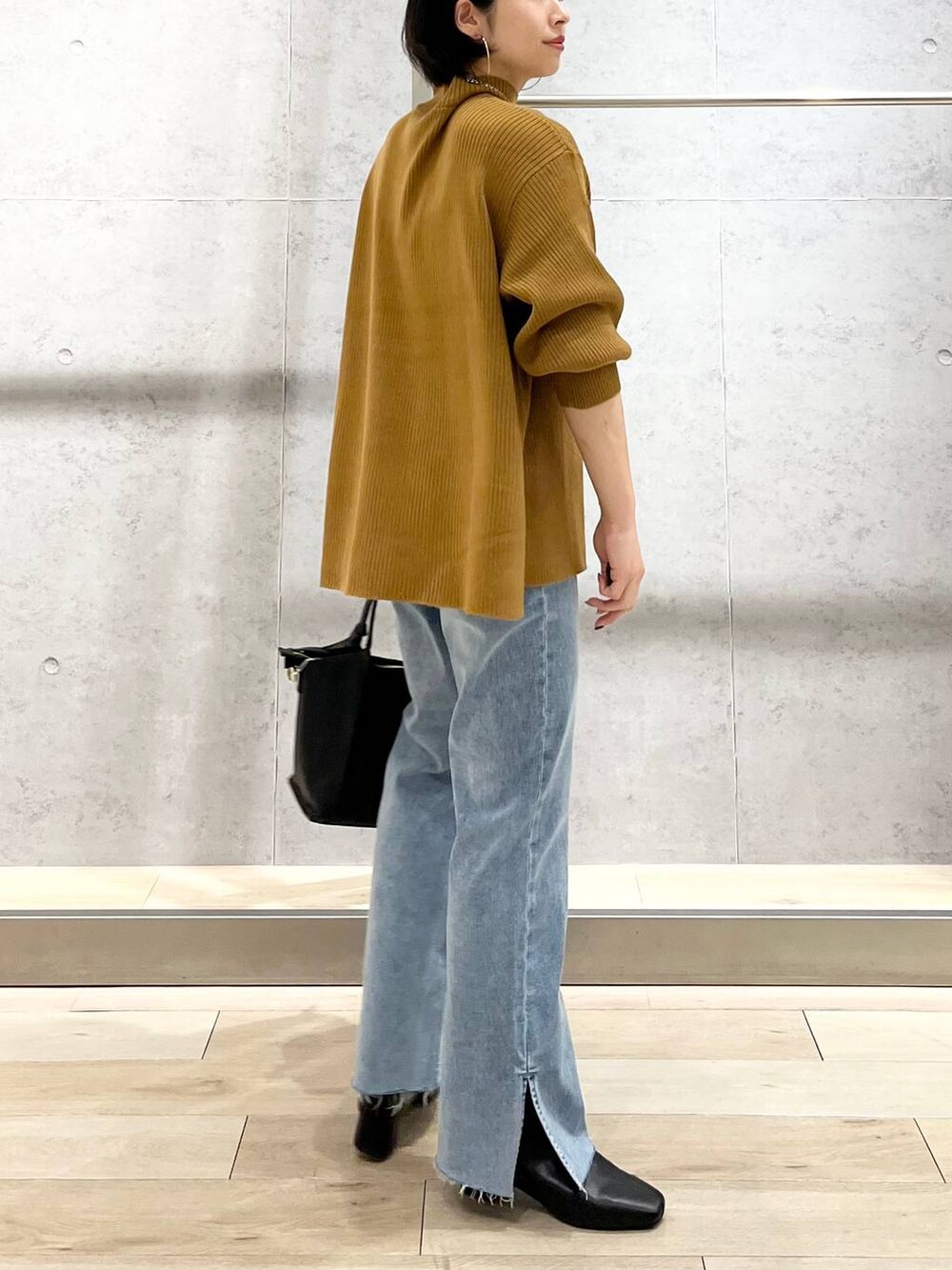 ブラウン系のニット/セーター、ブルー系のデニムパンツ、ベージュ系のショルダーバッグを着用したレディースの秋コーディネートの5枚目の写真