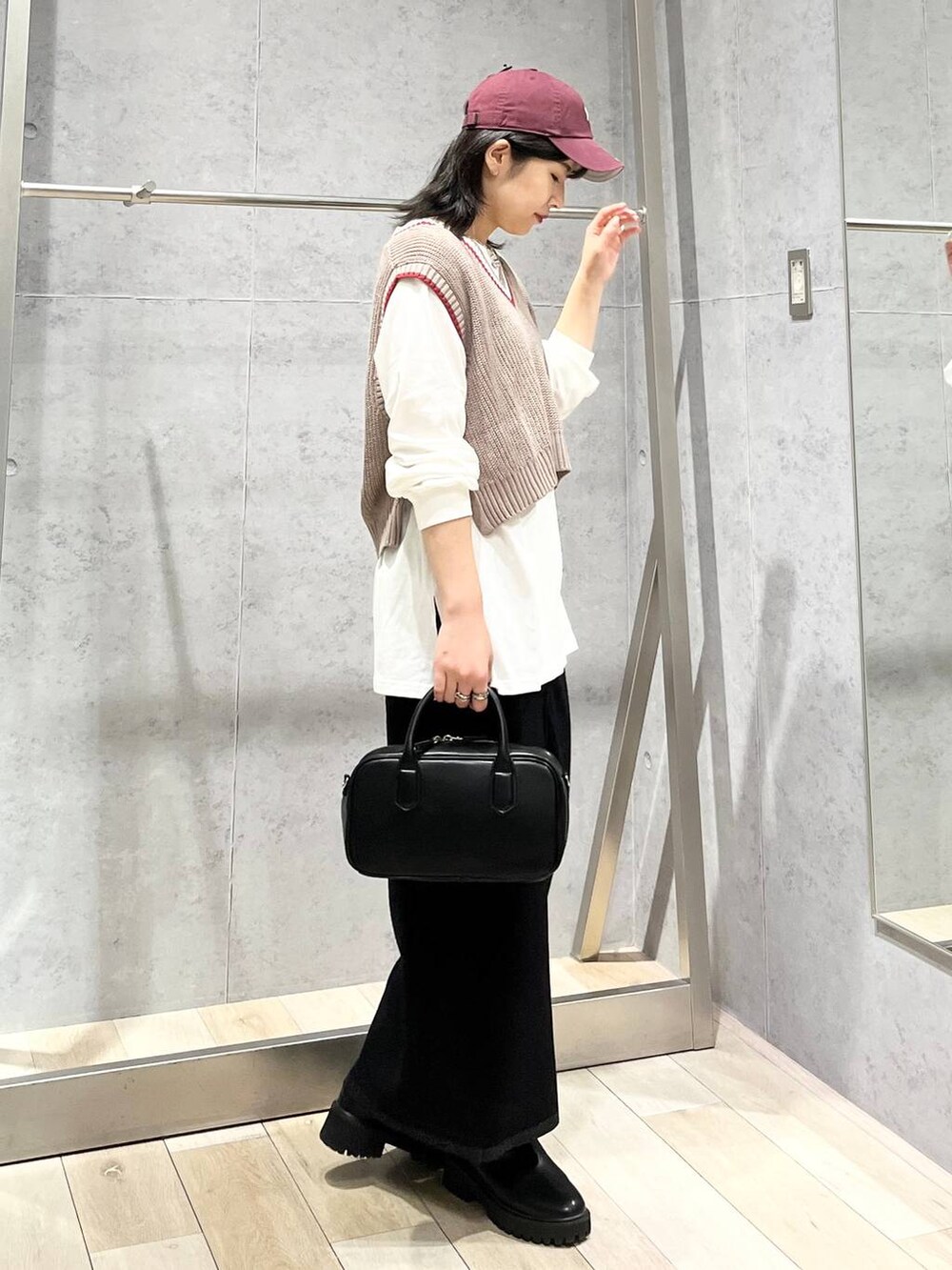 ブラック系のボストンバッグ、ブラック系のブーツ、ブラック系のスカートを着用したレディースの秋コーディネートの5枚目の写真