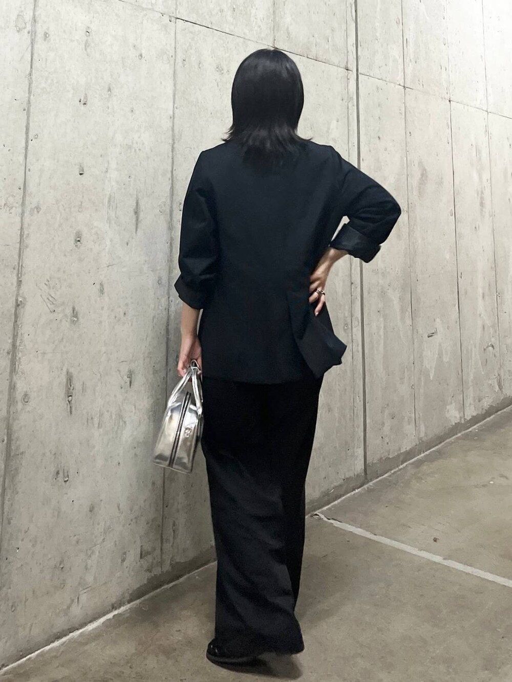 ブルー系のテーラードジャケット、シルバー系のボストンバッグ、グレー系のチノパンツを着用したレディースの秋コーディネートの4枚目の写真