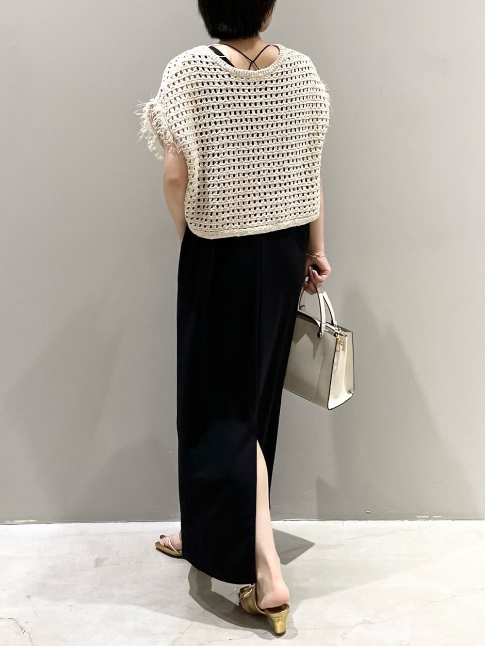 ホワイト系のショルダーバッグ、ブラック系のジャンパースカート、ゴールド系のサンダルを着用したレディースの夏コーディネートの7枚目の写真