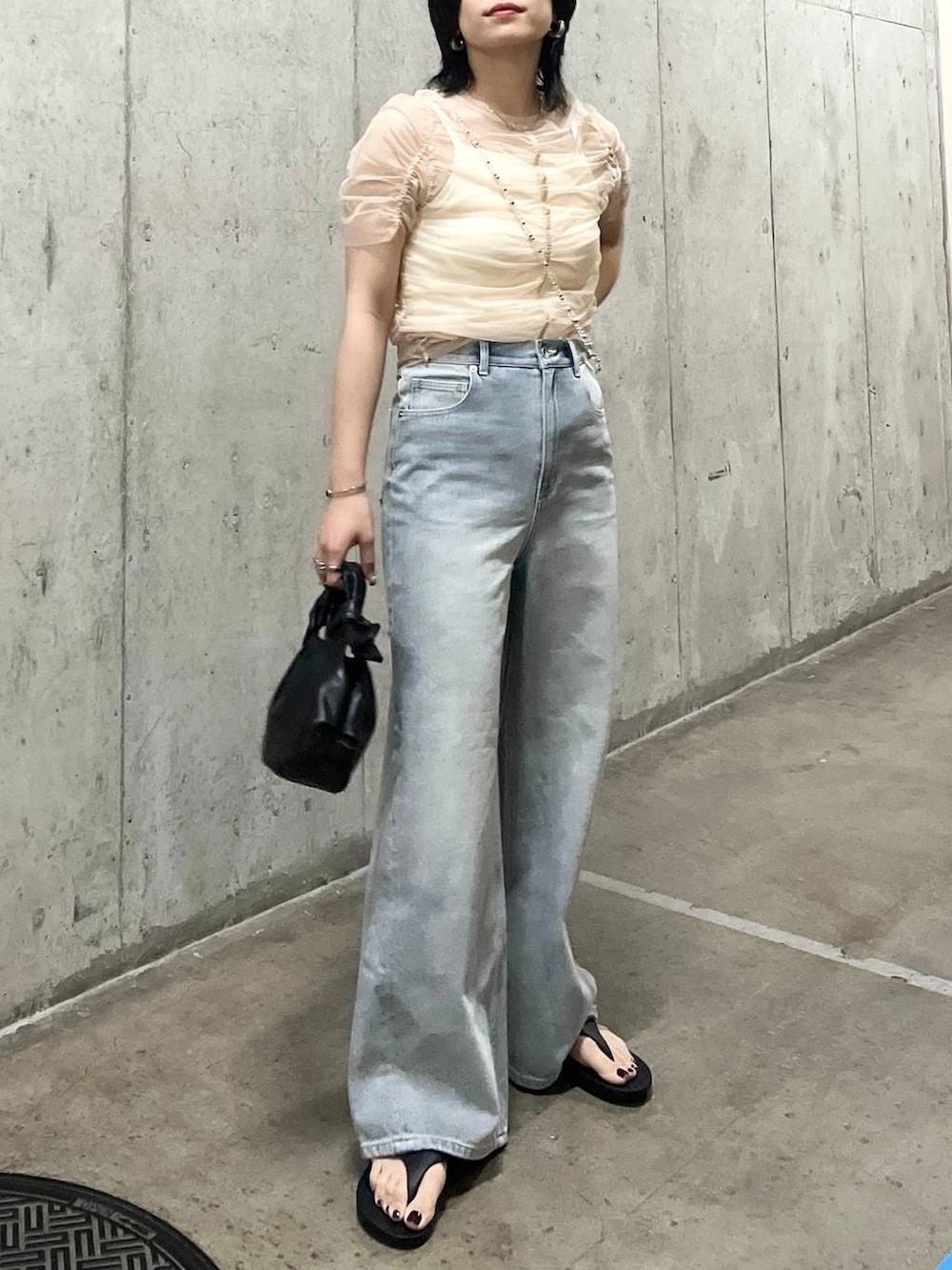 ホワイト系のキャミソール、ブルー系のデニムパンツ、ブラック系のサンダルを着用したレディースの夏コーディネートの2枚目の写真