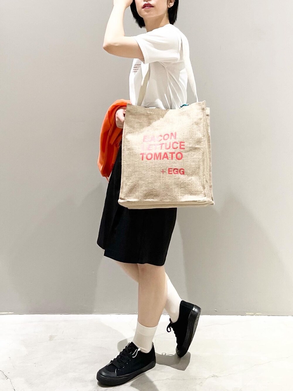 ブラック系のその他パンツ、ブラック系のスニーカー、オレンジ系のトートバッグを着用したレディースの夏コーディネートの4枚目の写真