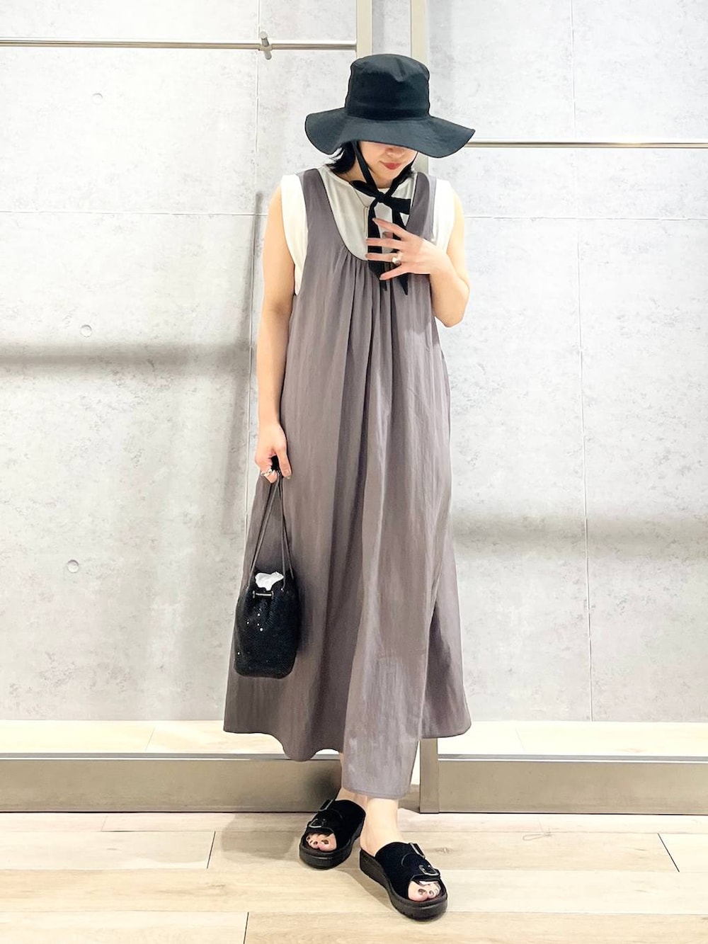 ブラック系のショルダーバッグ、ブラック系のサンダル、ホワイト系のTシャツ/カットソーを着用したレディースの夏コーディネートの2枚目の写真