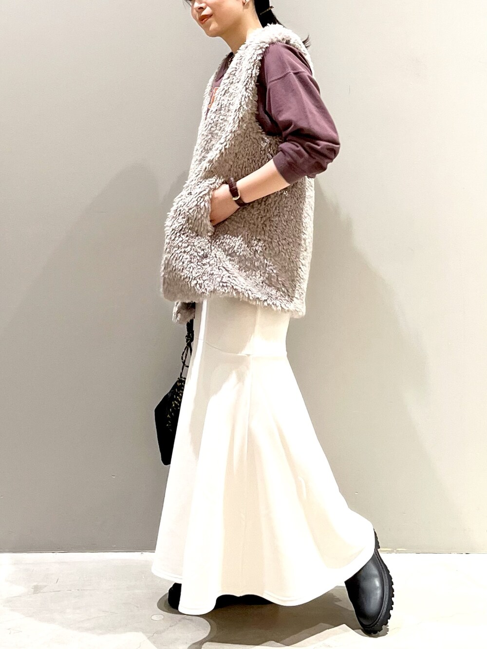 ホワイト系のスカート、ブラック系のブーツ、ブラック系のショルダーバッグを着用したレディースの秋コーディネートの2枚目の写真