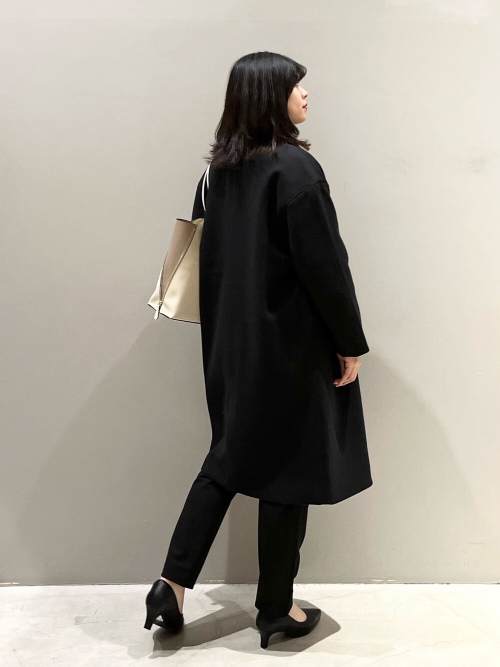 ブラック系のパンプス、ブラック系のパンツ、ブラック系のチェスターコートを着用したレディースの秋コーディネートの4枚目の写真