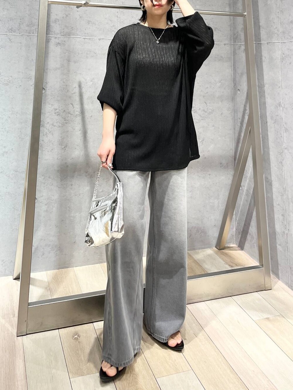 シルバー系のハンドバッグ、ブラック系のサンダル、グレー系のデニムパンツを着用したレディースの春コーディネートの3枚目の写真