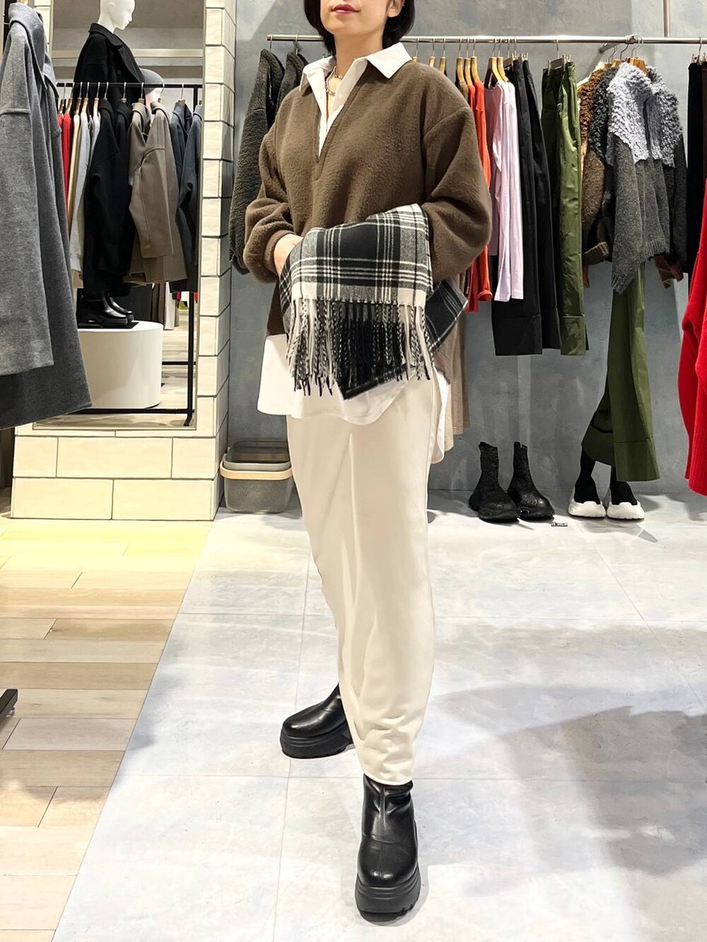 ホワイト系のスカート、ブラック系のブーツ、イエロー系のTシャツ/カットソーを着用したレディースの冬コーディネートの2枚目の写真