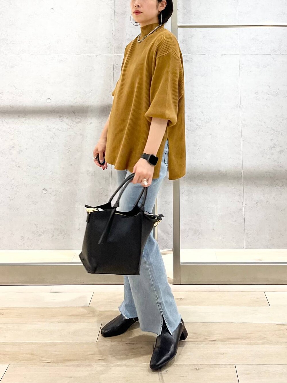 ブラウン系のニット/セーター、ブルー系のデニムパンツ、ベージュ系のショルダーバッグを着用したレディースの秋コーディネートの3枚目の写真