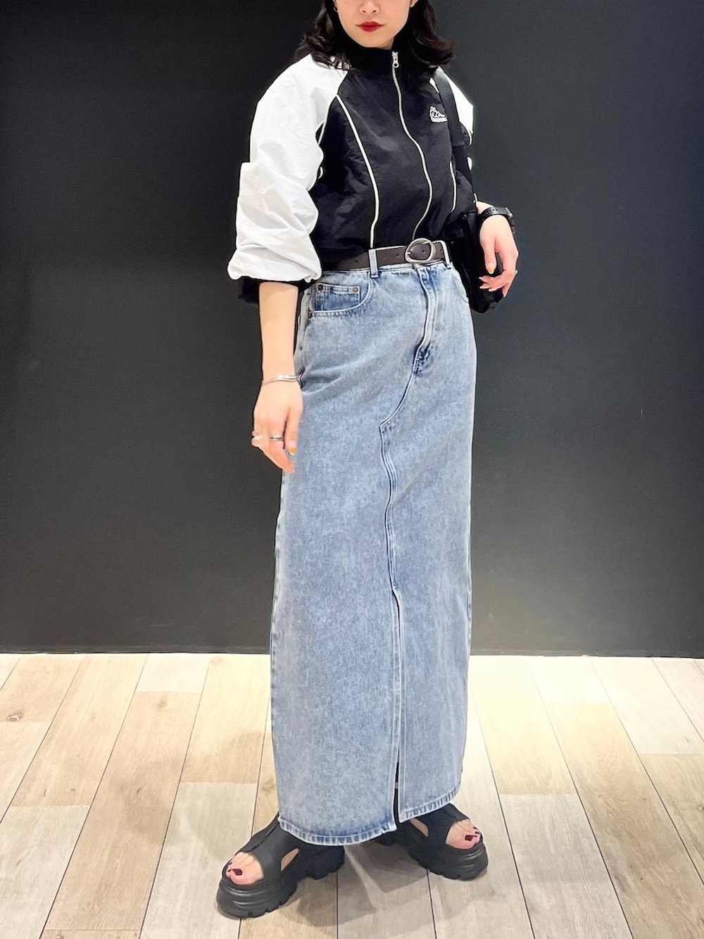 ブルー系のデニムスカート、ブラック系のショルダーバッグ、ブラック系のサンダルを着用したレディースの春コーディネートの4枚目の写真