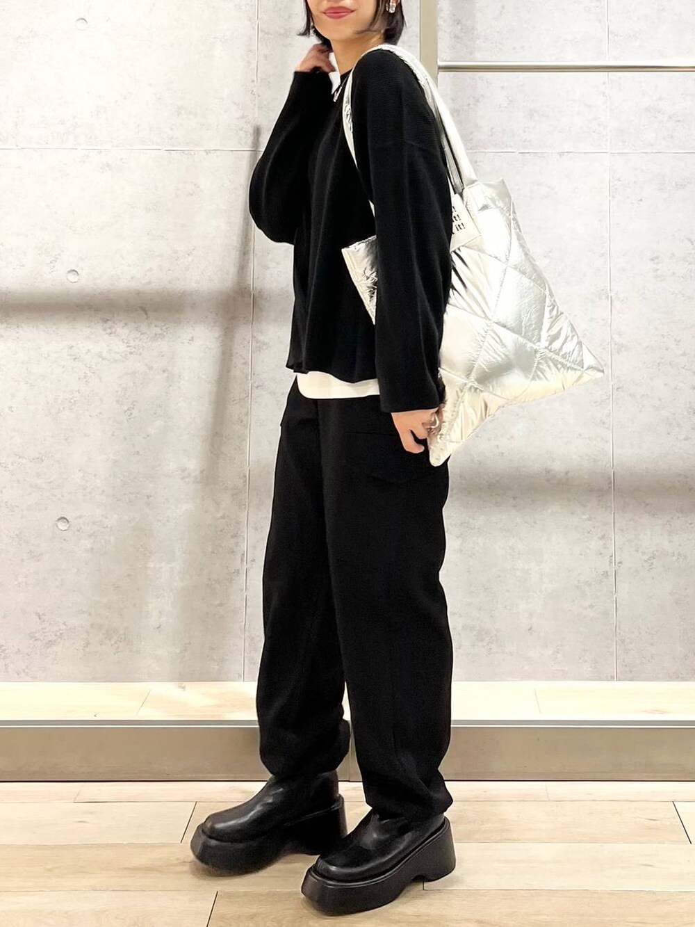 ブラック系のニット/セーター、ホワイト系のTシャツ/カットソー、ブラック系のブーツを着用したレディースの秋コーディネートの7枚目の写真