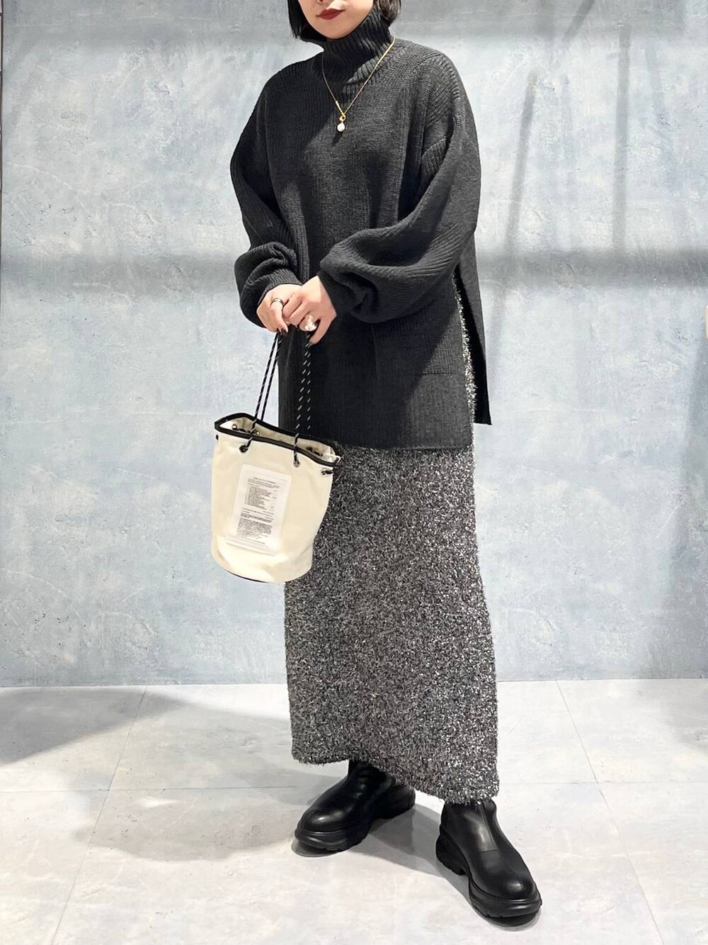 グレー系のTシャツ/カットソー、ブラック系のブーツ、ブラック系のスカートを着用したレディースの冬コーディネートの8枚目の写真