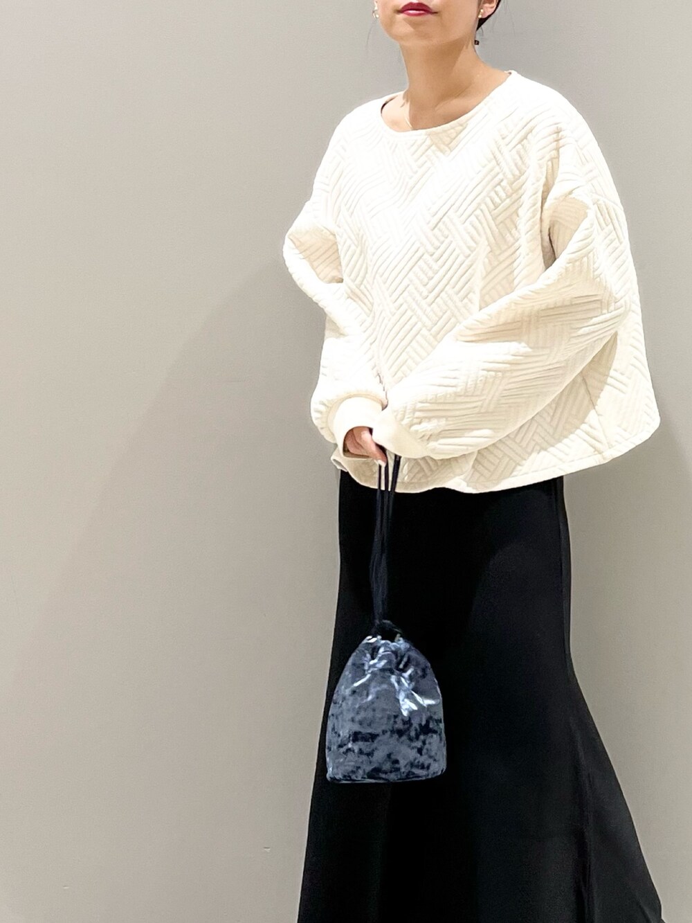 ブラック系のブーツ、ブラック系のスカート、ブルー系のショルダーバッグを着用したレディースの秋コーディネートの5枚目の写真