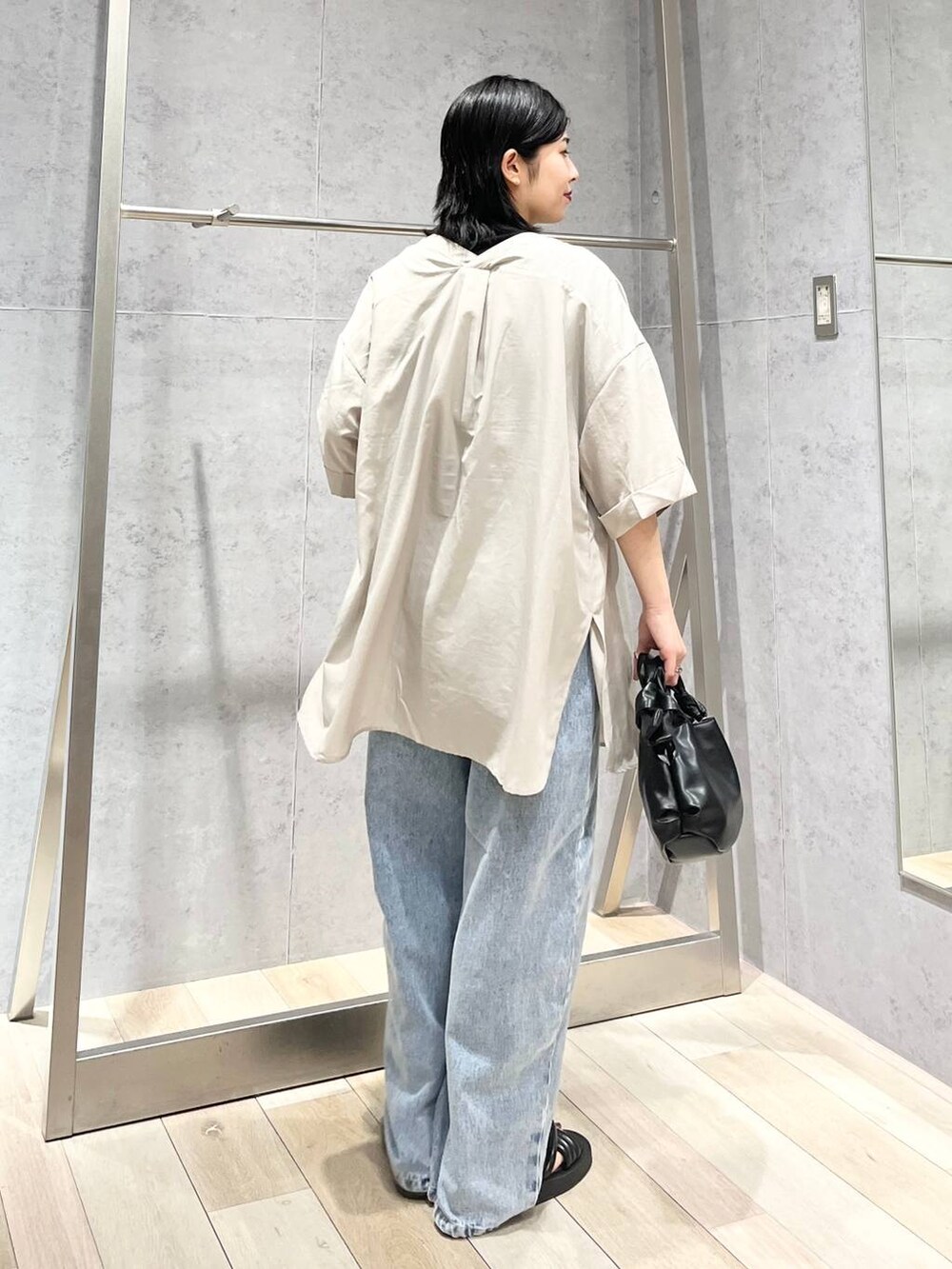 ブラック系のTシャツ/カットソー、ブラック系のサンダル、ブルー系のデニムパンツを着用したレディースの夏コーディネートの4枚目の写真