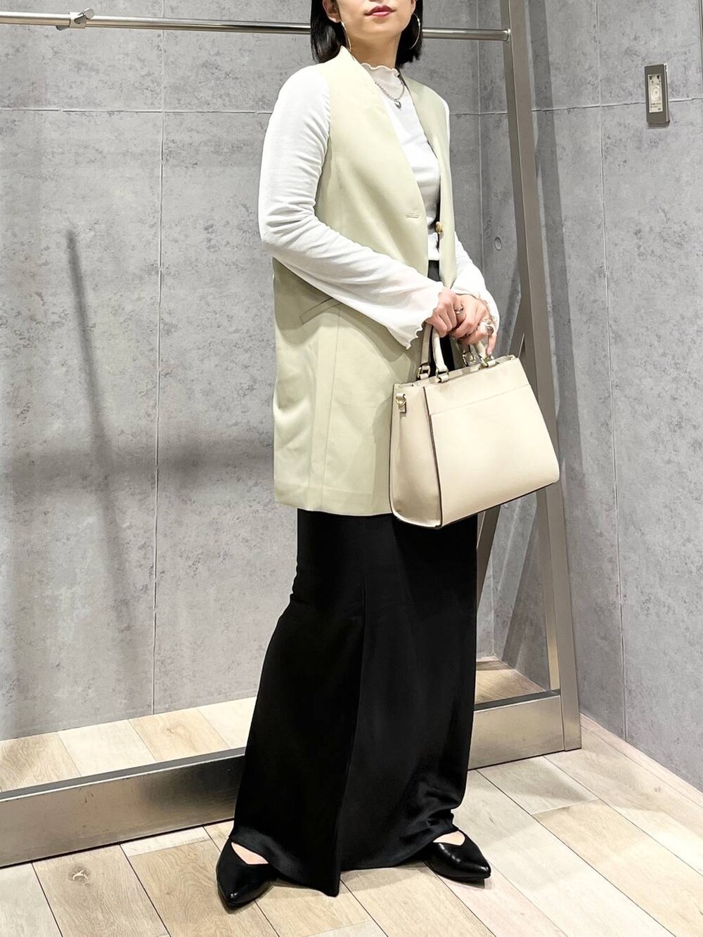 ホワイト系のTシャツ/カットソー、ブラック系のスカート、ホワイト系のショルダーバッグを着用したレディースの冬コーディネートの2枚目の写真