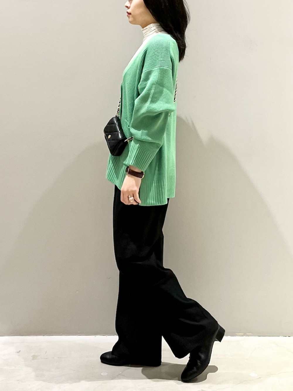 ブラック系のブーツ、ブラック系のスラックス、ブラック系のショルダーバッグを着用したレディースの秋コーディネートの4枚目の写真