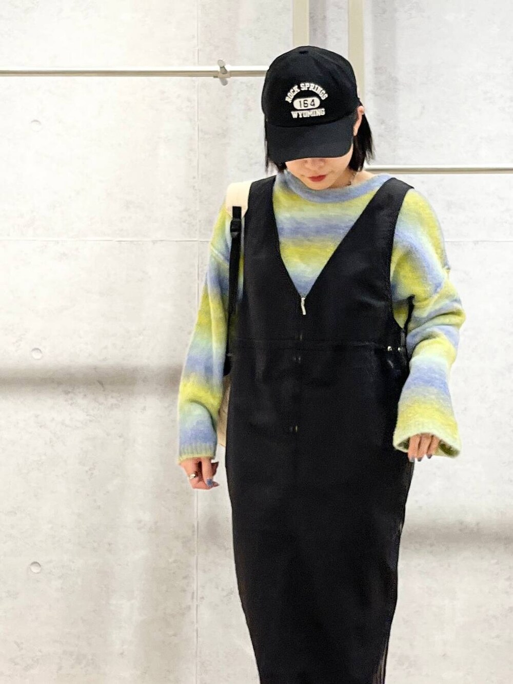 ホワイト系のバックパック/リュック、ブラック系のブーツ、ブラック系のジャンパースカートを着用したレディースの冬コーディネートの3枚目の写真