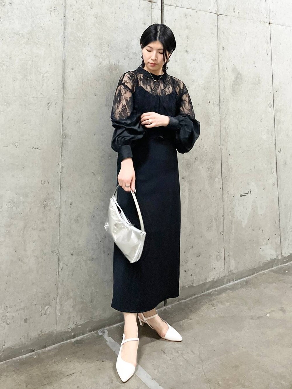 シルバー系のハンドバッグ、ホワイト系のパンプス、ゴールド系のネックレスを着用したレディースの春コーディネートの2枚目の写真